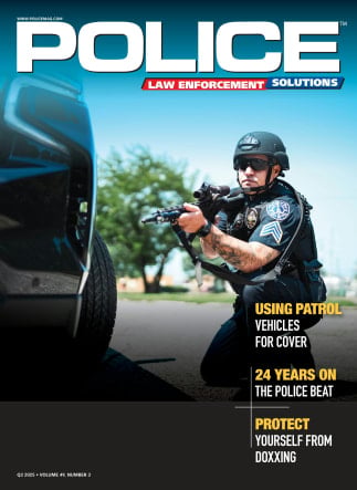Police officer in tactical gear using patrol vehicle for cover, aiming weapon