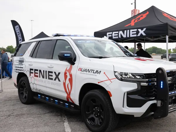 A white Chevrolet Tahoe PPV is on display with lights flashing.