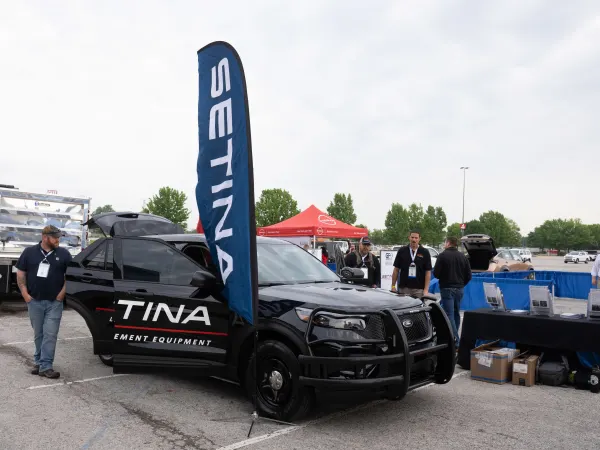 A black Ford Police Interceptor Utility with a Setina Manufacturing decal is shown with doors open and people gathered around.