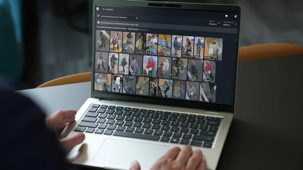 Image of a persons hands on keyboard of laptop with screen that displays multiple images from security cameras