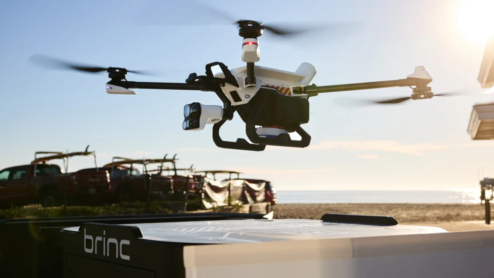 Police drone hovering over its charging nest against a blue sky background.