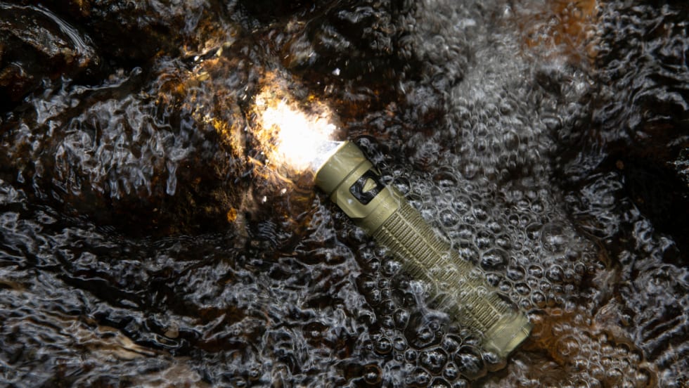 flashlight turn un and submerged in puddle with rain falling.