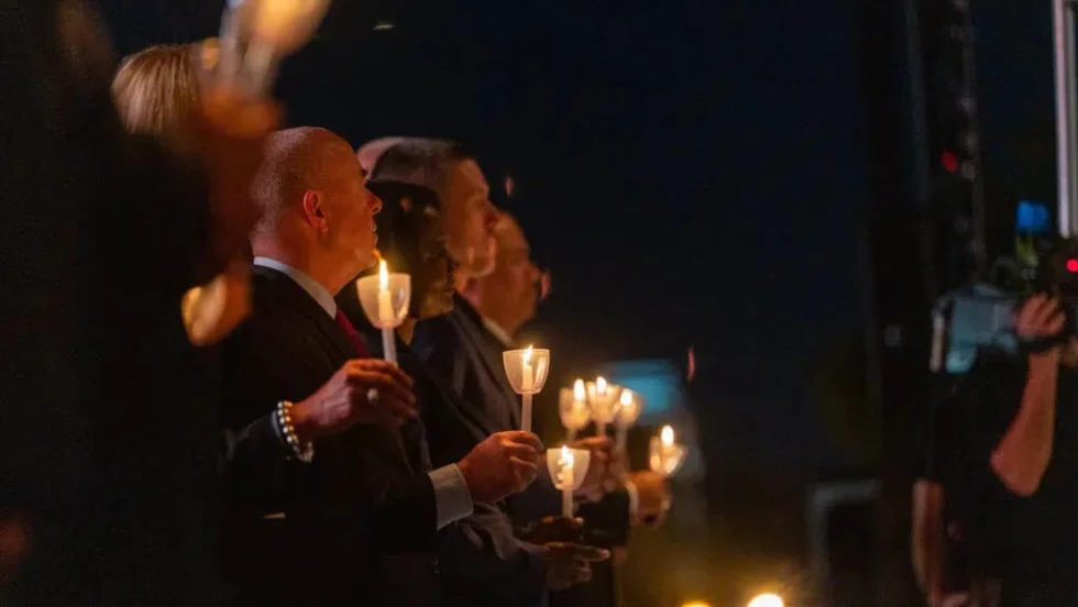 poeple dressed in dark clothing holding candles during a candlelight vigil.