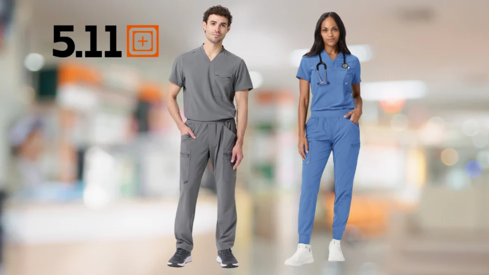Two healthcare professionals model 5.11 medical scrubs—one in gray and one in blue—against a blurred hospital background, highlighting the brand’s professional apparel for medical workers.