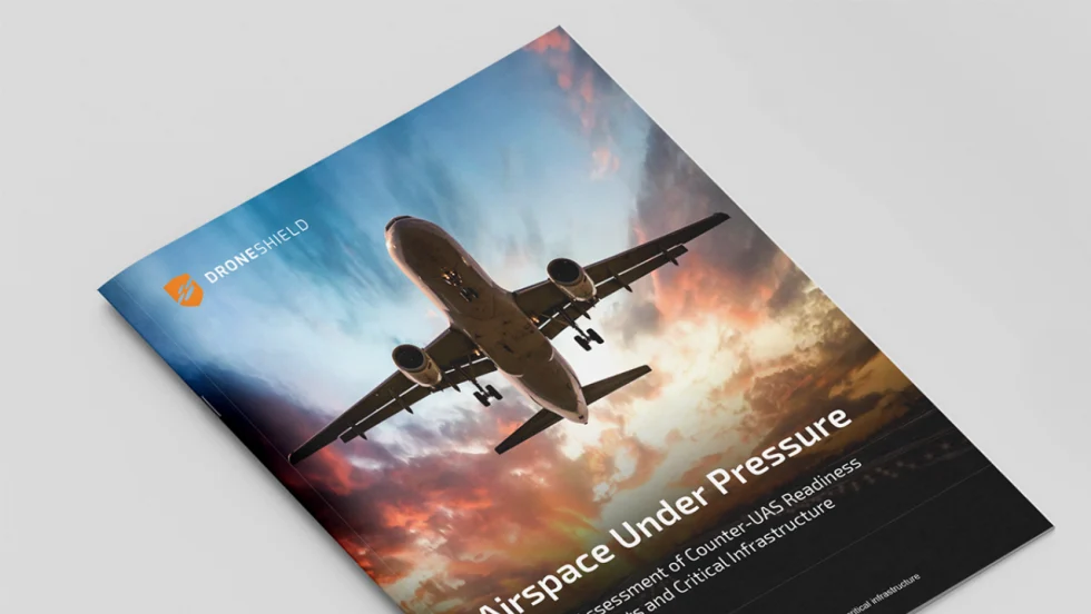 DroneShield report cover featuring a commercial airliner in flight against a dramatic sky. The publication, Airspace Under Pressure, focuses on counter-UAS readiness for airports and critical infrastructure.