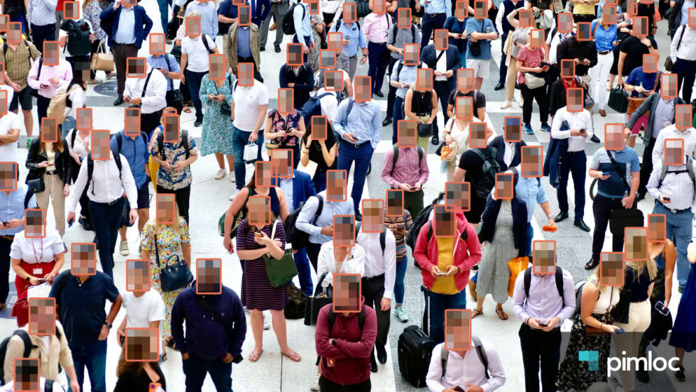Overhead view of a crowded public space with AI-generated boxes obscuring faces, illustrating automated facial anonymization and privacy protection in video surveillance. Pimloc logo appears in the lower-right corner.