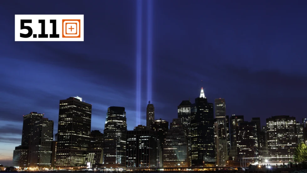 New York City skyline at night with the Tribute in Light beams illuminating the sky in remembrance of September 11, with the 5.11 logo in the upper left.