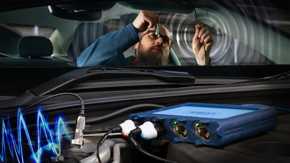 Technician using PicoScope NVH diagnostic device inside a vehicle, connecting sensors to measure vibration and noise from engine components.