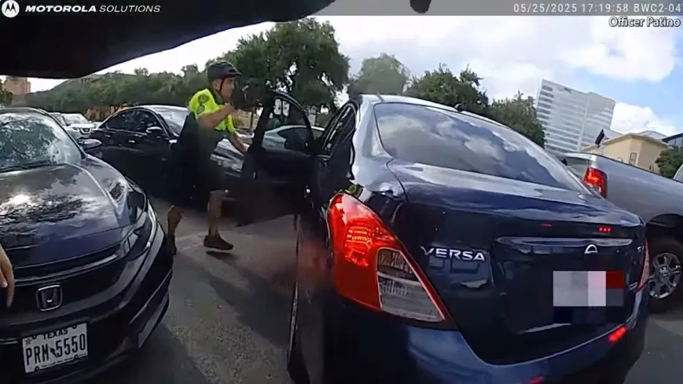 Dashcam view of traffic stop with police officer near dark blue Nissan Versa