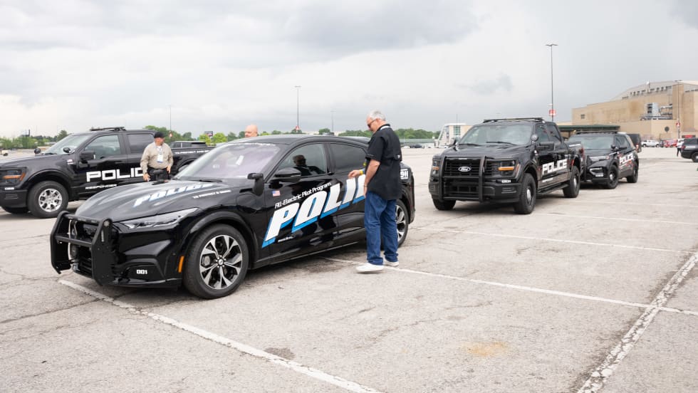 A lineup of police vehicles waiting to be test-driven is shown. They include a Ford Mustang Mach-E, a Ford F-150 Police Responder, and a Ford Police Interceptor Utility.