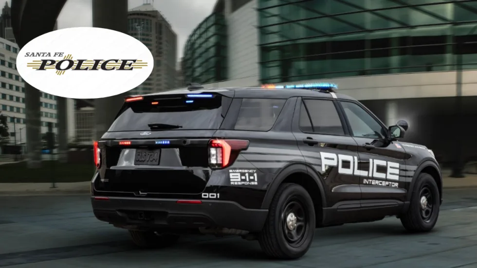 A black Ford Police Interceptor Utility is shown driving down a road.