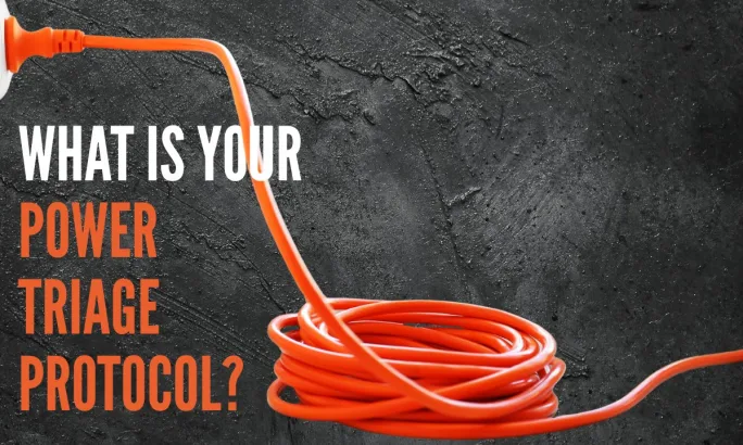 Orange extension cord plugged in on dark background representing fleet power triage and prioritizing critical equipment during a power outage