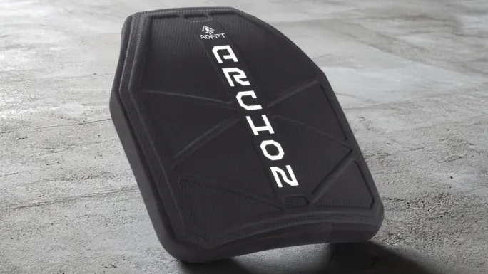 Close-up of an Adept Armor Archon protective plate featuring a black textured surface, angular reinforced pattern, and prominent white Archon branding, positioned on a concrete floor.