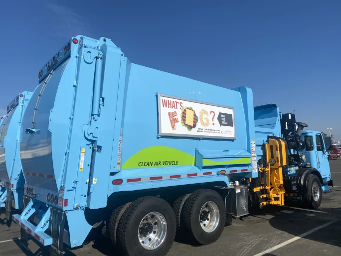 A refuse truck with signage.