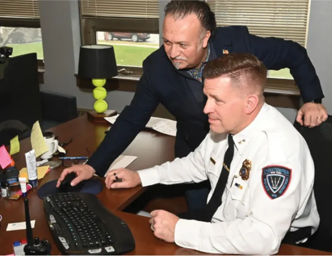 Executive with a police chief showing the software on his computer.