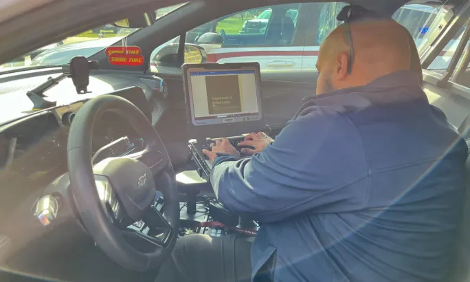 Alabama A&M police officer seated inside an electric patrol vehicle using a mounted laptop computer.