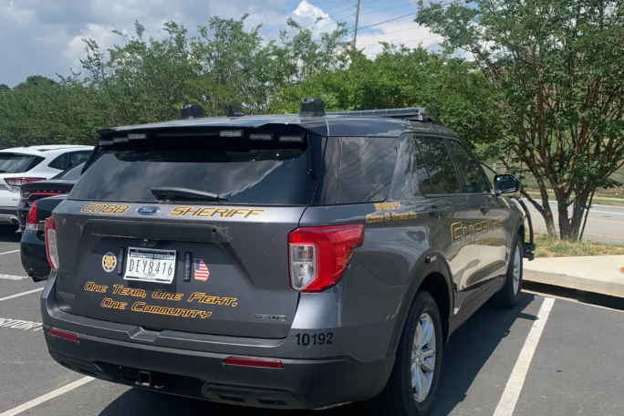 A gray Ford PIU Hybrid with a gold Cobb County Sheriff's Office decal sits in a parking lot.