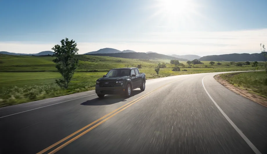 A black Ford Maverick XL is shown driving down a rural road.