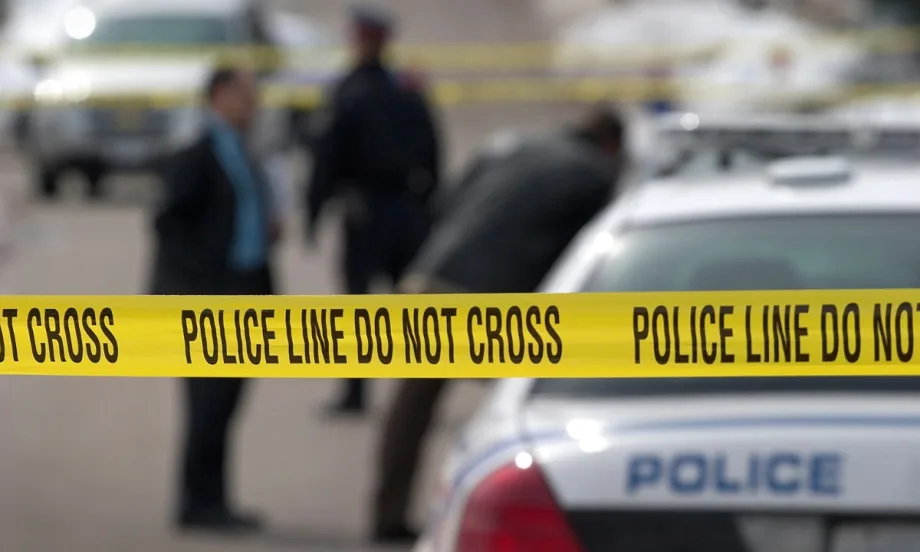 Yellow police tape cordoning off a crime scene with police vehicle