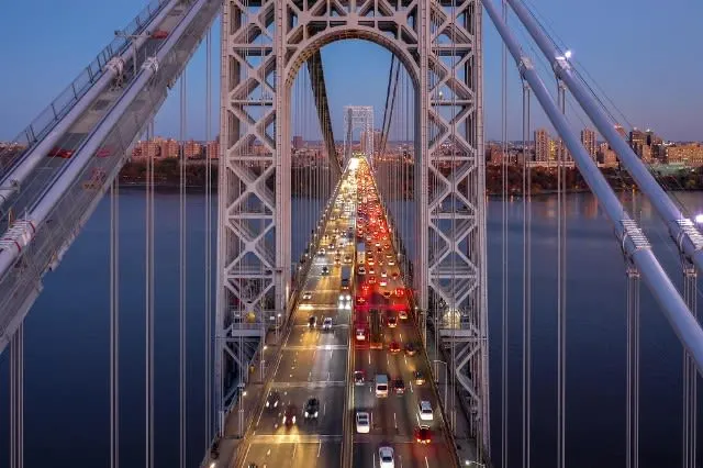 High-angle view of cars with lights turned on crossing the George Washington Bridge at dusk.