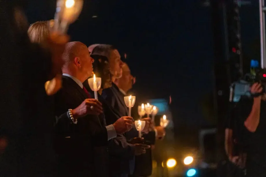 poeple dressed in dark clothing holding candles during a candlelight vigil.