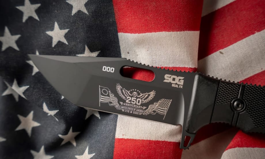 Close-up of a black SOG Seal FX knife featuring a commemorative 250th anniversary engraving on the blade, displayed on an American flag to honor the United States' semiquincentennial.