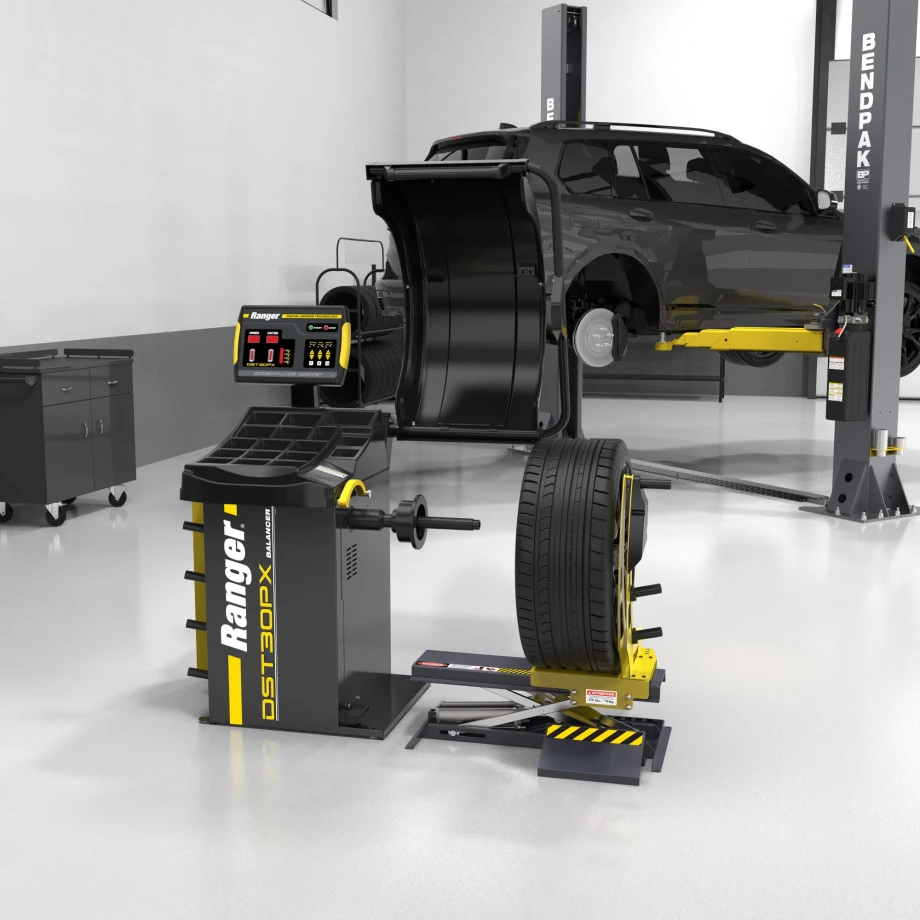 Ranger wheel balancer and pneumatic wheel lift installed in a vehicle service shop next to an SUV on a lift.